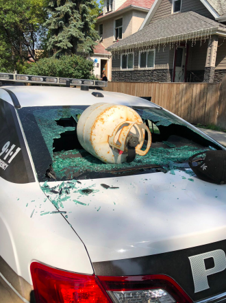 A man throws propane tank at a police cruiser